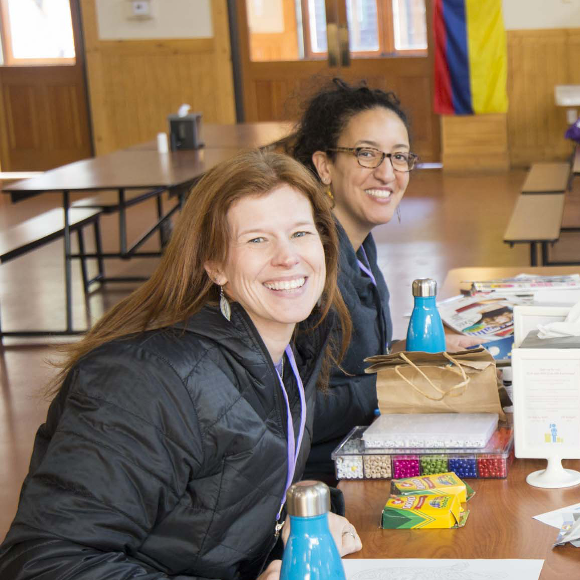 two women at a craft table smiling