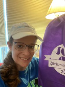 A photo of the blogger wearing a white cap that says "Girls with Guts" in blue. She is holding up a purple bag with the GWG logo.