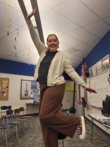 Emily stands in front of a classroom smiling. 